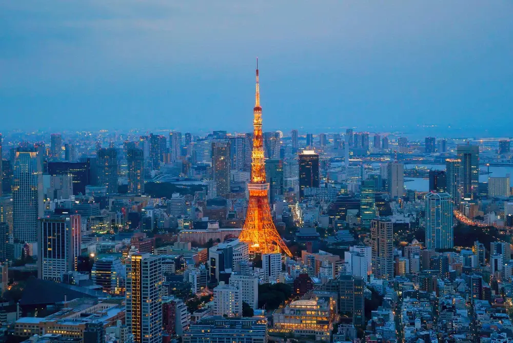 aerial view of the Tokyo skyline at dusk, prominently featuring the illuminated Tokyo Tower.